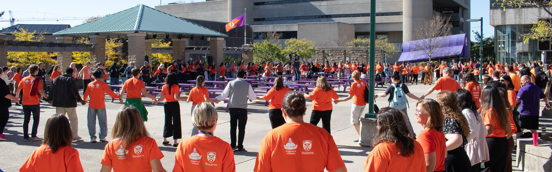 people wear orange shirts and holding hands in a circle