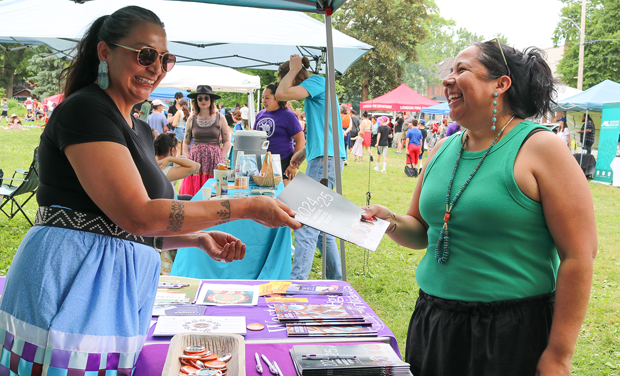 Paula Cornelius-Hedgepeth Director, Indigenous Engagement and Wampum Learning Lodge, handing a copy of the annual report to a community member