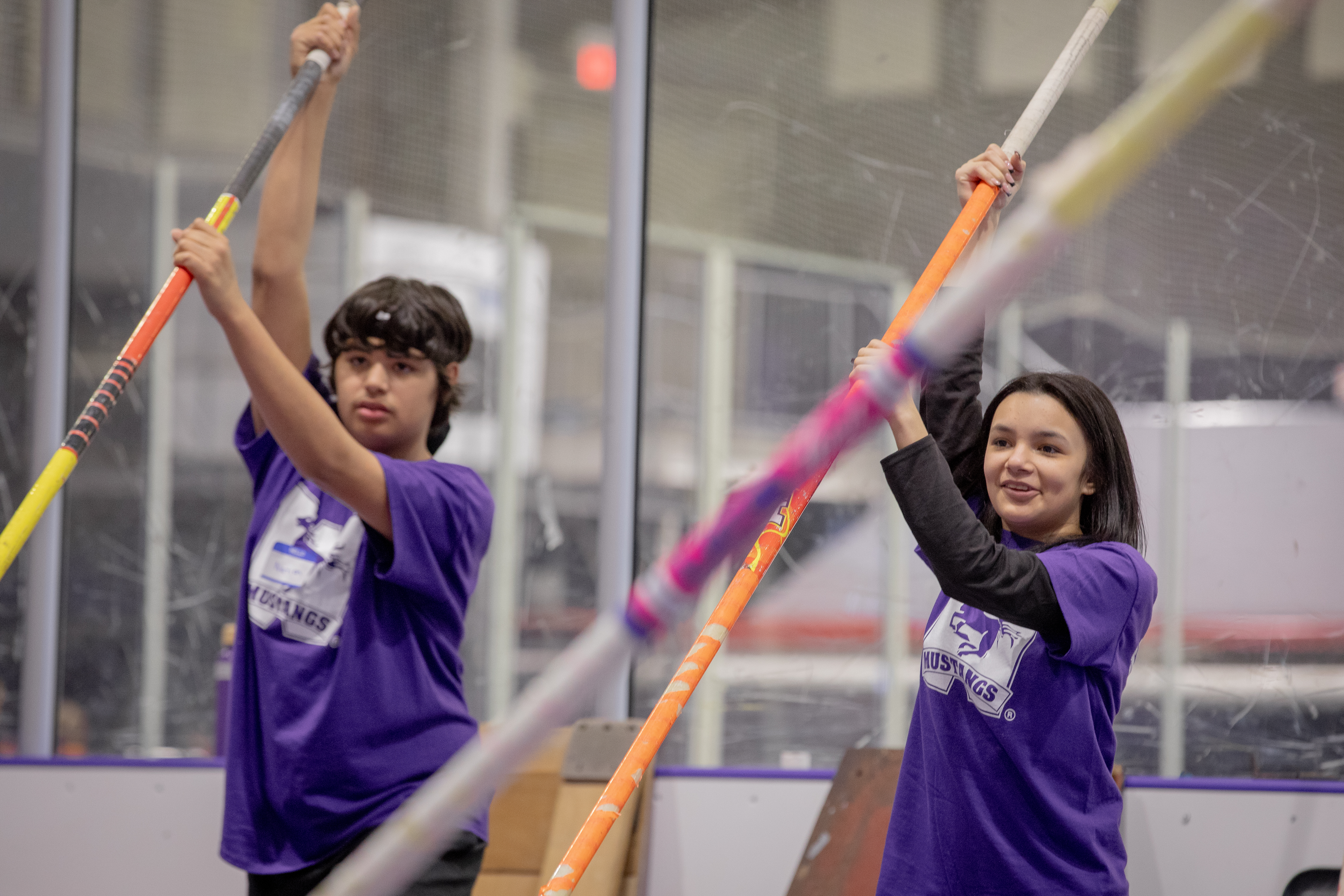two indigenous youth holding pole vaulting sticks